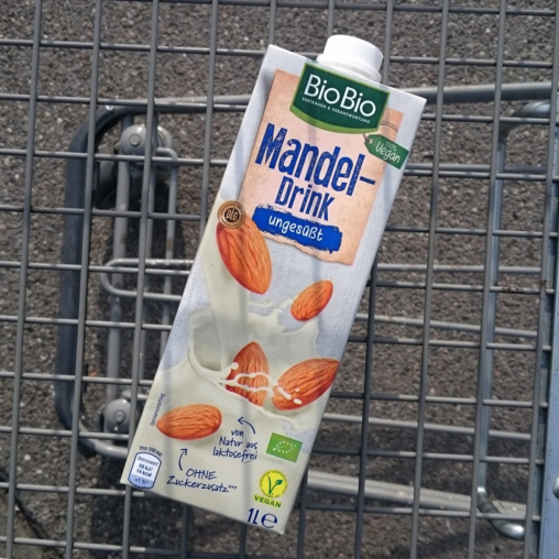 A pack of almond drink in a shopping cart.